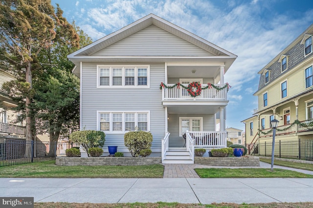 view of front of home featuring a balcony, a front lawn, and a porch