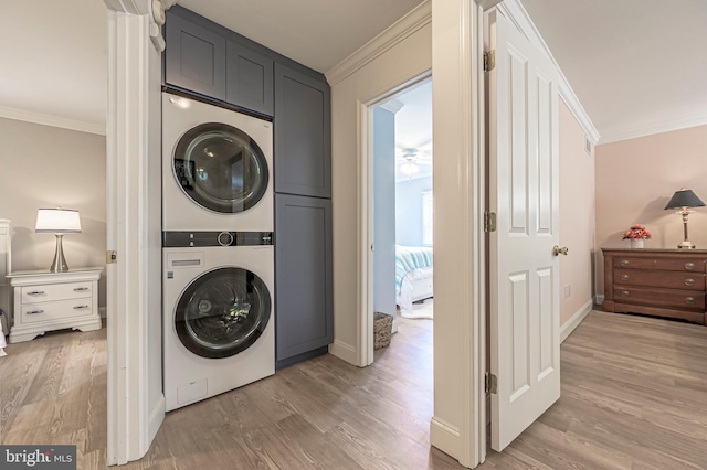 laundry area featuring crown molding, cabinets, hardwood / wood-style floors, and stacked washing maching and dryer