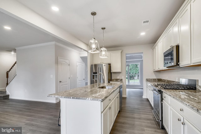 kitchen with a center island with sink, decorative light fixtures, light stone counters, and appliances with stainless steel finishes