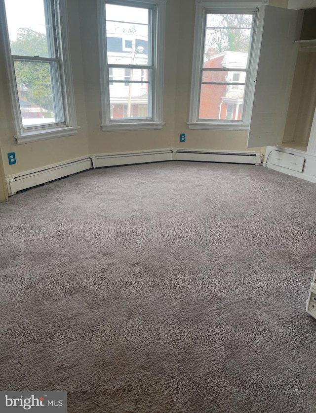 carpeted empty room with a healthy amount of sunlight and a baseboard radiator