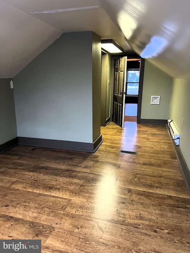 additional living space with hardwood / wood-style floors, lofted ceiling, and a baseboard heating unit