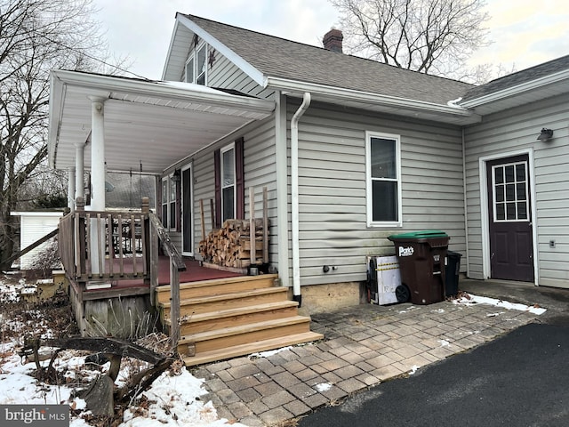 snow covered property entrance with a porch