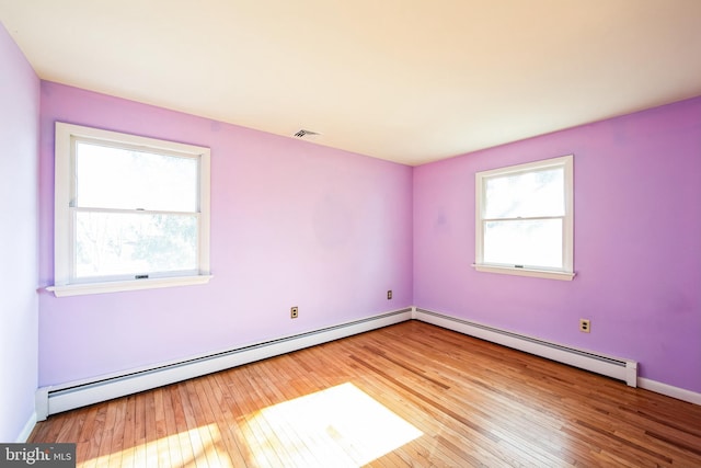 spare room with baseboard heating and light wood-type flooring