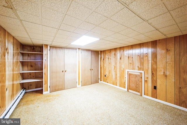 basement featuring baseboard heating, carpet floors, and wood walls