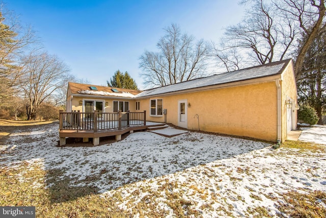 snow covered rear of property with a deck