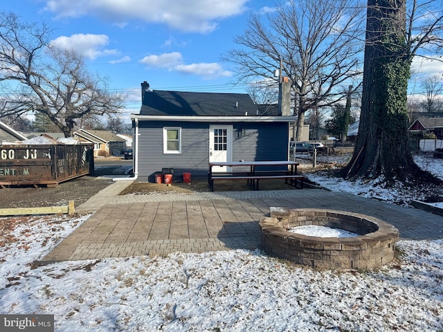 snow covered house featuring a deck and an outdoor fire pit