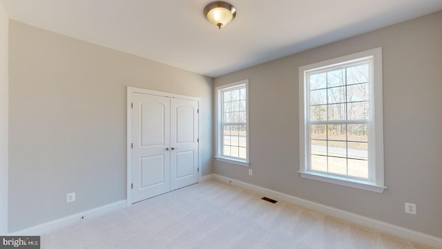 unfurnished bedroom with a closet and light colored carpet