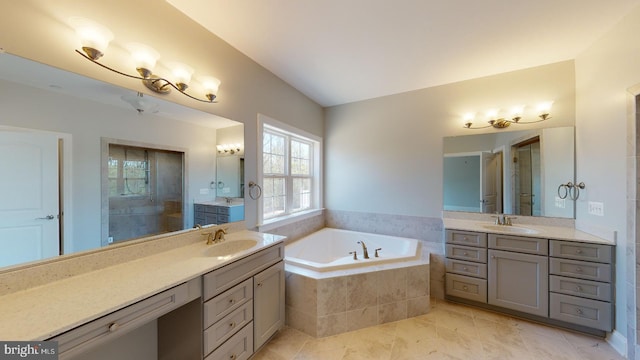 bathroom featuring tile patterned flooring, vanity, and a relaxing tiled tub