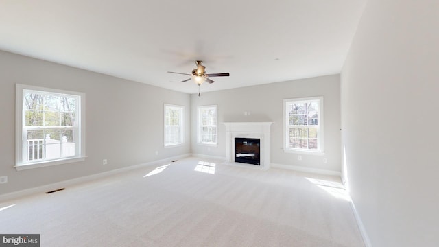 unfurnished living room with plenty of natural light, ceiling fan, and light carpet