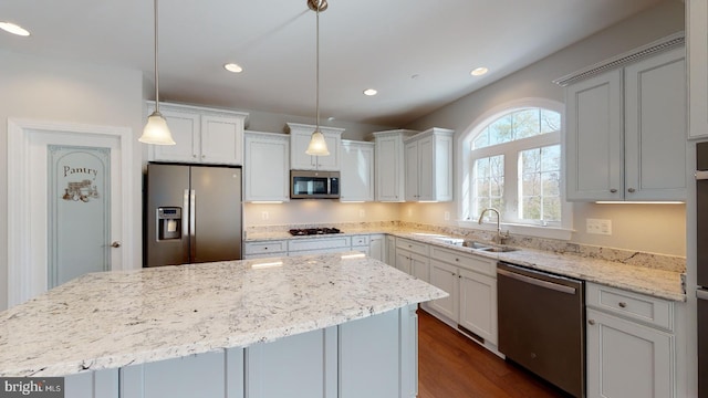 kitchen with pendant lighting, a center island, stainless steel appliances, and sink