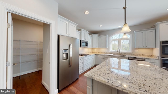 kitchen featuring dark hardwood / wood-style flooring, white cabinets, decorative light fixtures, and appliances with stainless steel finishes