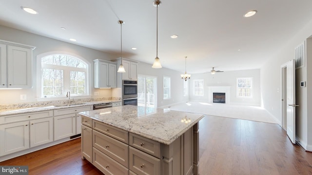 kitchen featuring white cabinetry, sink, a kitchen island, and decorative light fixtures