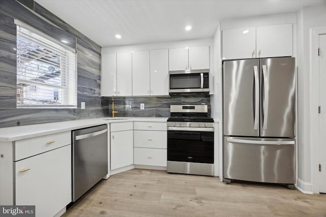 kitchen featuring white cabinets, appliances with stainless steel finishes, light wood-type flooring, and sink