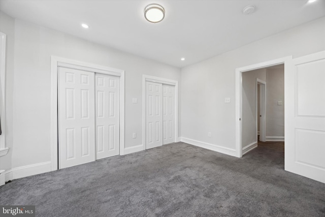 unfurnished bedroom with two closets and dark carpet