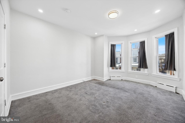 carpeted spare room with a baseboard heating unit