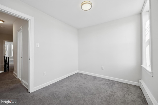 unfurnished room with dark carpet and baseboard heating