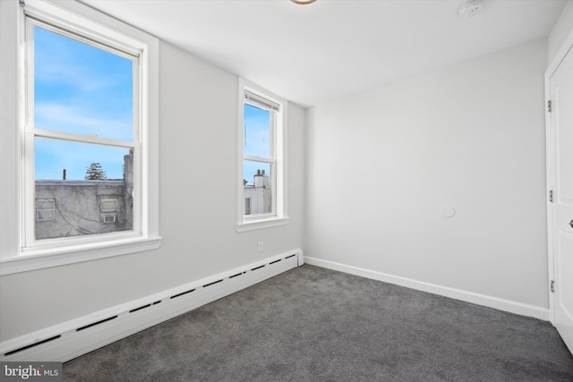 unfurnished room with baseboard heating and dark carpet