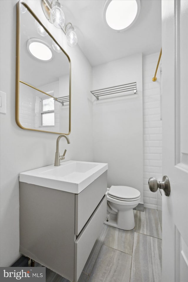 bathroom with a shower, vanity, and toilet