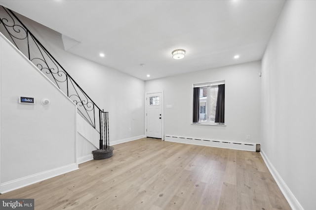 foyer with light wood-type flooring and a baseboard heating unit