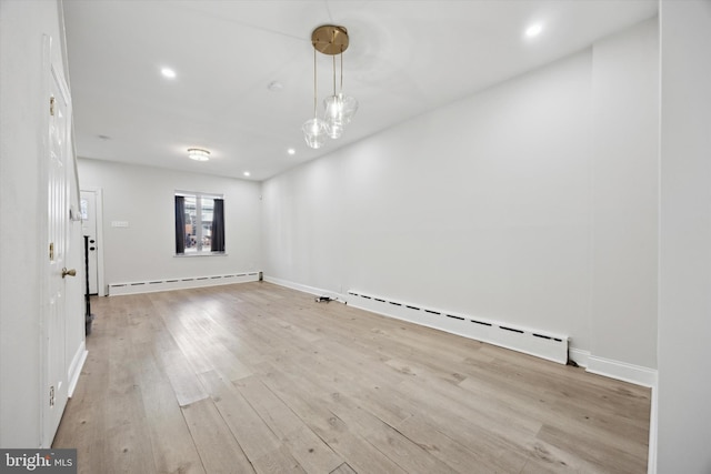 unfurnished room featuring light hardwood / wood-style flooring and a baseboard heating unit