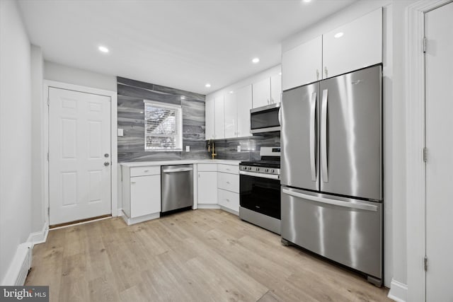 kitchen featuring backsplash, light hardwood / wood-style floors, white cabinetry, and stainless steel appliances