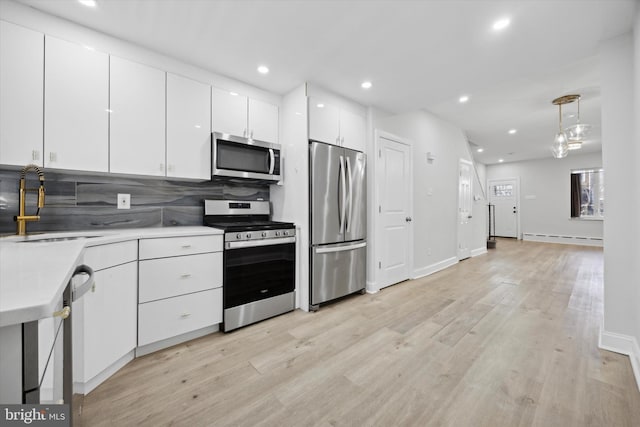 kitchen with sink, a baseboard radiator, tasteful backsplash, white cabinets, and appliances with stainless steel finishes