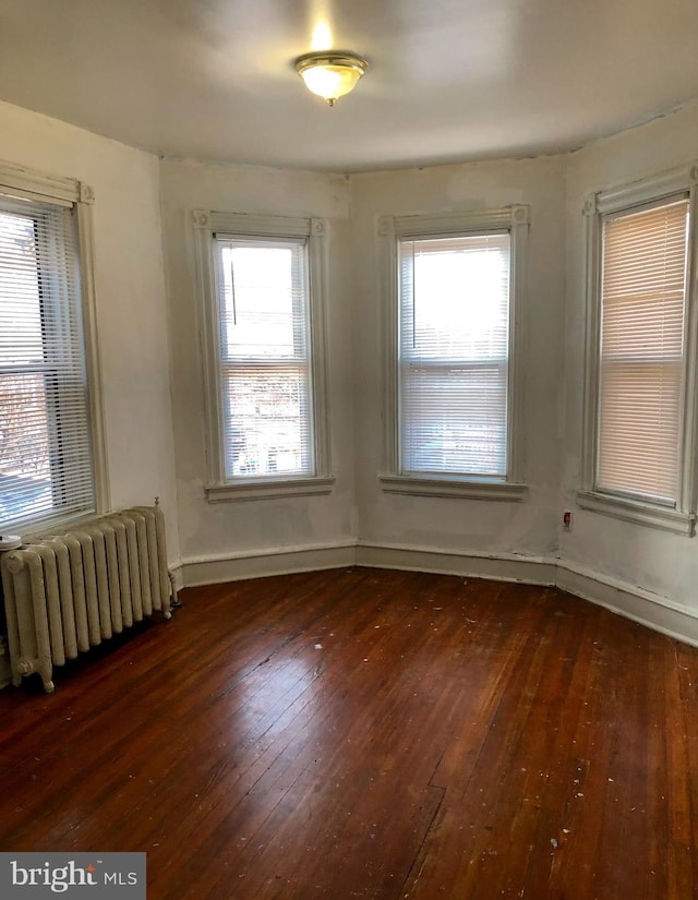 spare room with dark hardwood / wood-style floors, plenty of natural light, and radiator