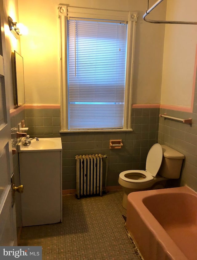 bathroom featuring radiator, tile patterned flooring, vanity, and tile walls