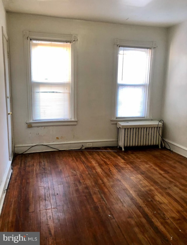 unfurnished room with radiator, dark hardwood / wood-style flooring, and a healthy amount of sunlight