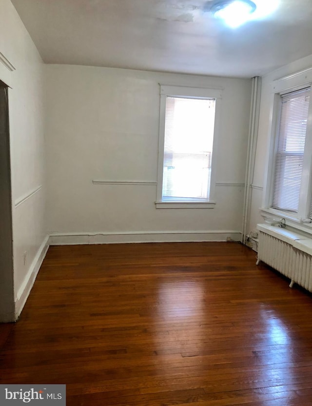 spare room featuring radiator and dark hardwood / wood-style flooring