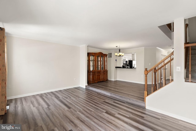 unfurnished living room with a chandelier and dark hardwood / wood-style floors