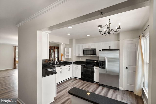 kitchen featuring white cabinets, wood-type flooring, stainless steel appliances, and a chandelier