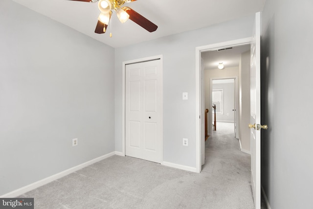 unfurnished bedroom featuring ceiling fan, a closet, and light colored carpet