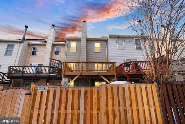 back house at dusk with a wooden deck