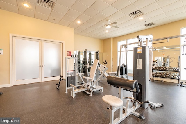 workout area featuring a paneled ceiling, ceiling fan, and a healthy amount of sunlight