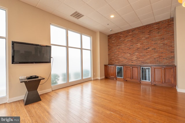 unfurnished living room with light wood-type flooring, plenty of natural light, and brick wall