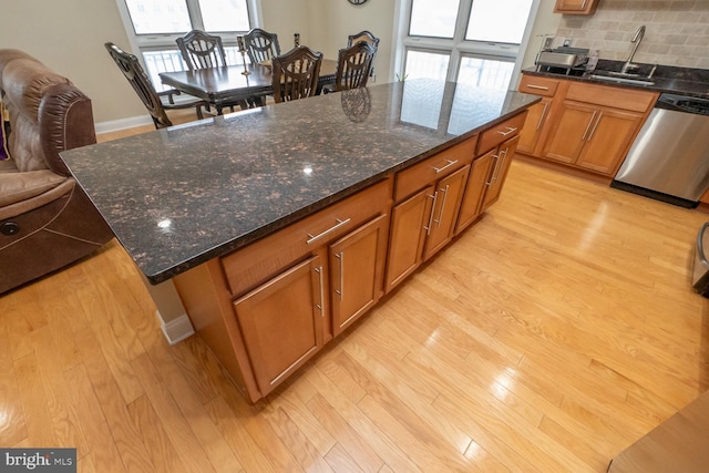 kitchen featuring sink, stainless steel dishwasher, plenty of natural light, a kitchen island, and light wood-type flooring