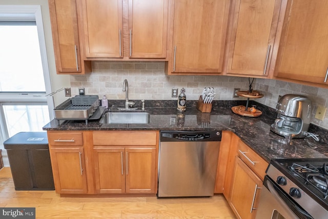 kitchen with decorative backsplash, sink, stainless steel appliances, and dark stone counters