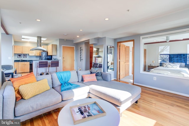 living area with light wood-style floors, ceiling fan, baseboards, and recessed lighting