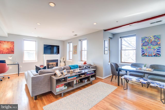 living area featuring recessed lighting, visible vents, wood finished floors, and a glass covered fireplace