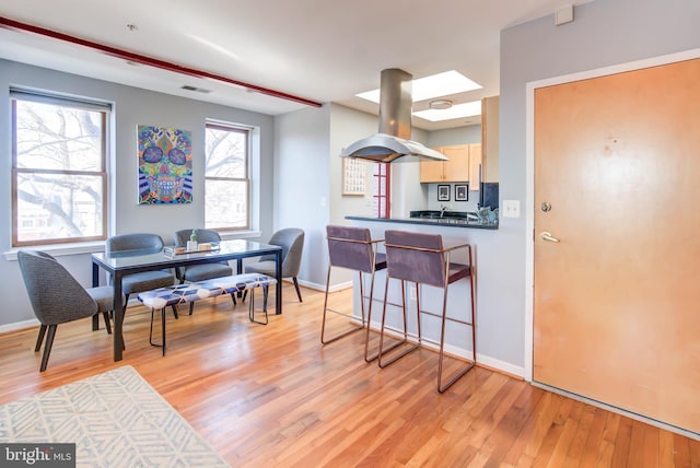 kitchen featuring baseboards, visible vents, island exhaust hood, and light wood finished floors