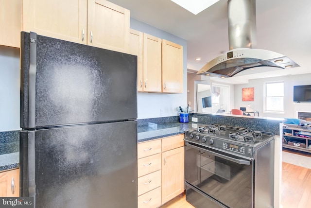 kitchen with dark countertops, light brown cabinetry, open floor plan, island range hood, and black appliances