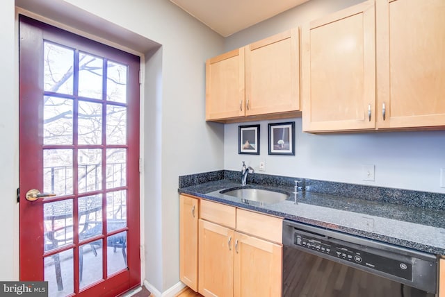 kitchen featuring dishwasher, light brown cabinetry, dark stone counters, and a sink