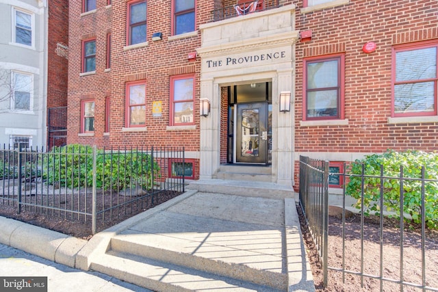 entrance to property featuring brick siding and fence