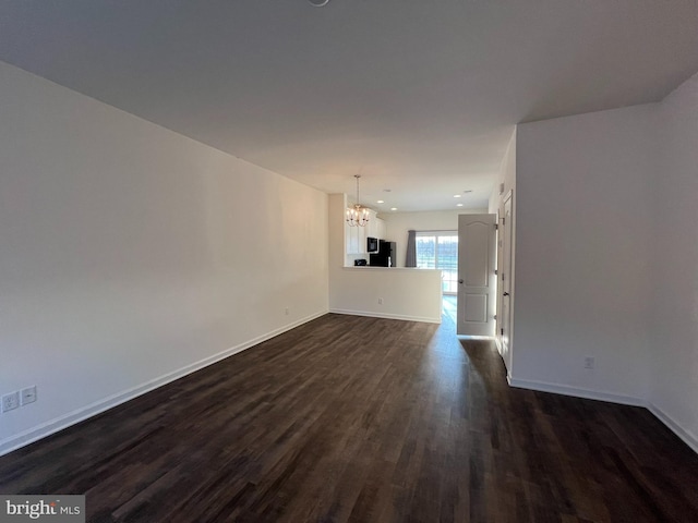 unfurnished living room featuring a chandelier and dark wood-type flooring