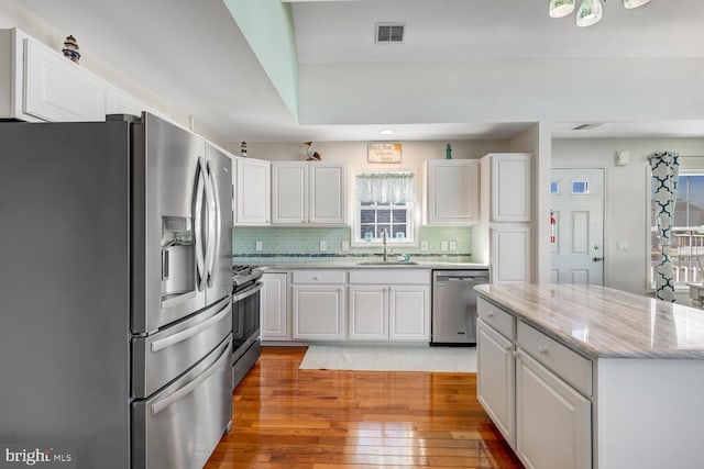 kitchen with stainless steel appliances, white cabinets, and sink