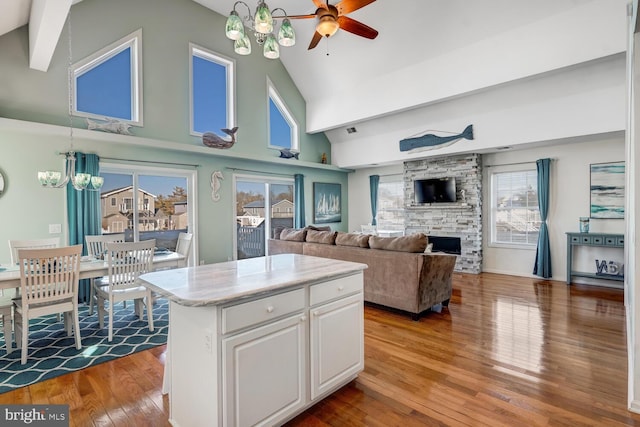 kitchen featuring light hardwood / wood-style flooring, a center island, high vaulted ceiling, white cabinetry, and ceiling fan with notable chandelier