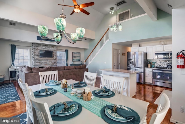 dining area with ceiling fan with notable chandelier, high vaulted ceiling, beam ceiling, and dark hardwood / wood-style flooring