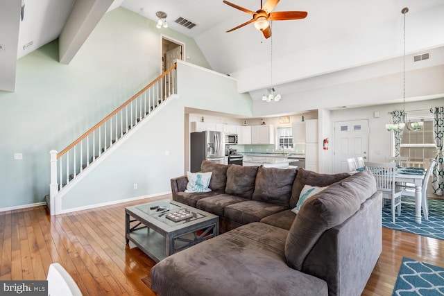 living room featuring light hardwood / wood-style flooring, high vaulted ceiling, and ceiling fan with notable chandelier