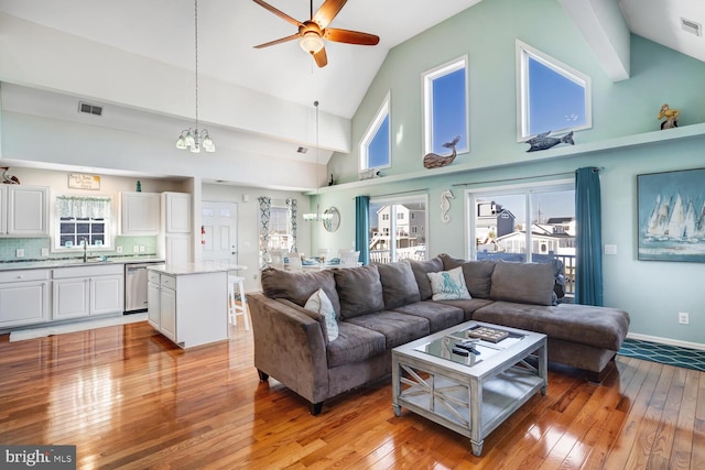 living room featuring high vaulted ceiling, ceiling fan, light hardwood / wood-style flooring, and sink